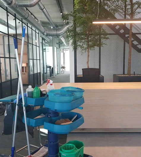Schoonmaakkar met materialen in een kantoorpand